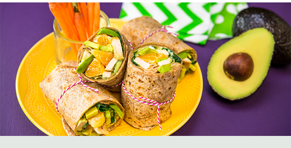 Fresh vegetable, fruit, and avocado wrap with a side of carrots.